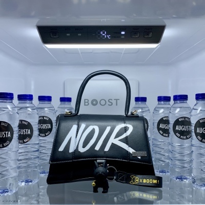 Interior de frigorífico com garrafas de água AUGUSTA e mala preta com escrita NOIR.