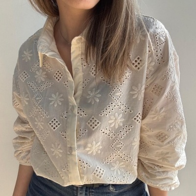 Blusa branca bordada com mangas compridas e botões, usada com jeans.