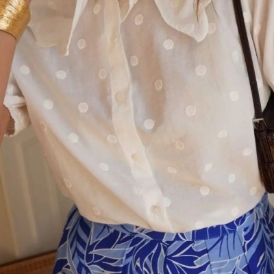 Camisa branca com bolinhas e saia azul com padrão de folhas
