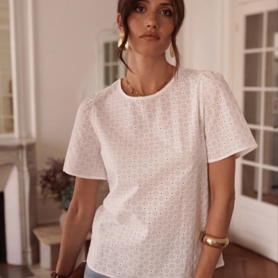 Mulher com camisola branca e calças de ganga num interior decorado