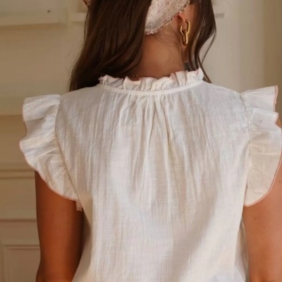 Mulher vista de costas com blusa branca com folhos e lenço floral na cabeça