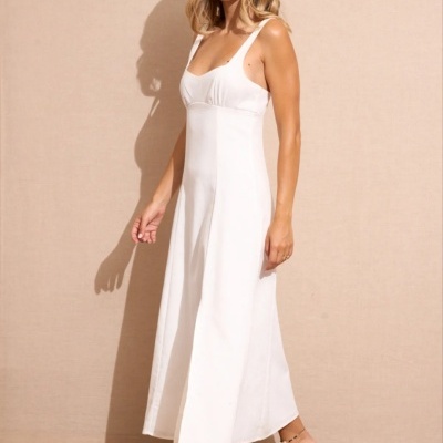 Mulher vestindo vestido longo branco com alças largas e sapatos rasteiros bege com flor