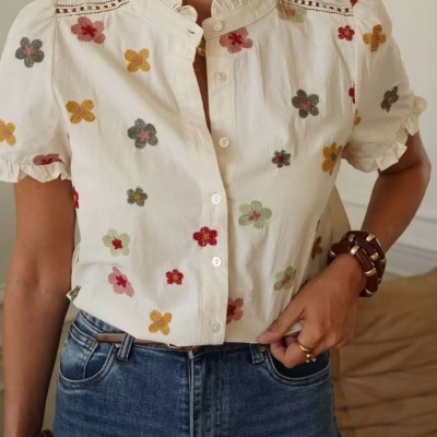 Blusa branca com flores bordadas e botões, combinada com jeans azuis