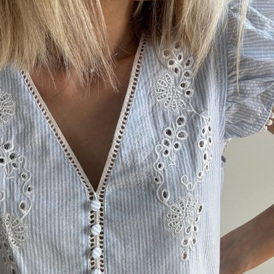 Blusa feminina azul claro às riscas com bordados brancos e botões forrados.