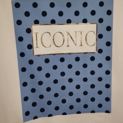 Tecido branco com aplicação azul de bolinhas pretas e texto ICONIC dourado