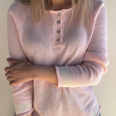 Camisola rosa clara de malha fina com botões prateados e mangas compridas vestida por pessoa.