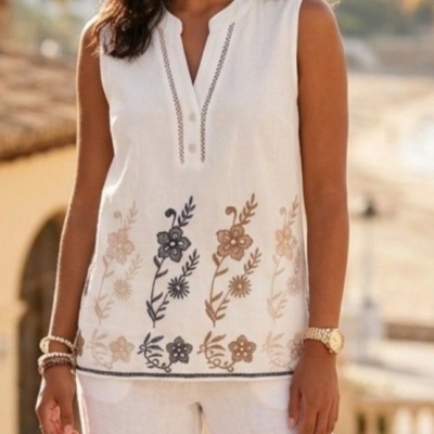 Blusa branca sem mangas com bordados florais castanhos e bege e calças brancas