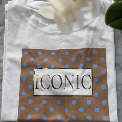 T-shirt branca com estampa castanha e pontos azuis, texto dourado ICONIC