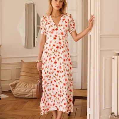 Vestido comprido branco com flores vermelhas e verdes usado por mulher em ambiente interior clássico