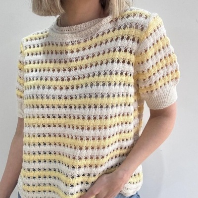 Camisola de malha creme e amarelo com padrão aberto e calças de ganga azuis