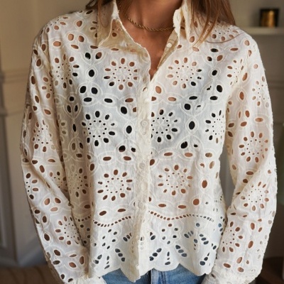 Camisa branca bordada com padrão floral e círculos, botões frontais, gola e bainha ondulada.