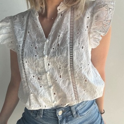 Blusa branca bordada com detalhes em renda e folhos nas mangas, com calças de ganga azul