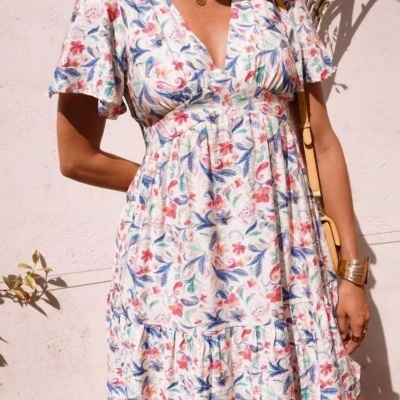 Vestido curto floral com decote em V e mangas curtas, com mulher e acessórios em fundo claro