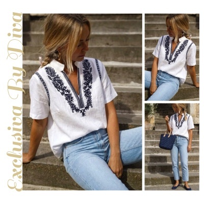 Mulher com blusa branca bordada em azul e jeans sentada em escadas de pedra.