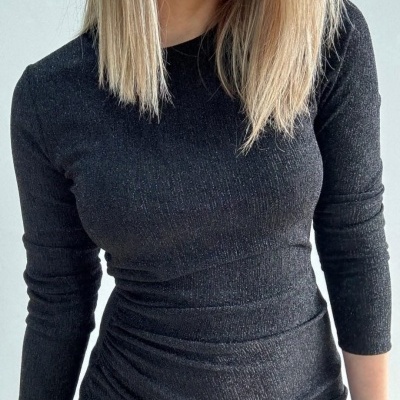 Blusa preta de manga comprida com textura canelada e brilho sutil, mulher com cabelo loiro
