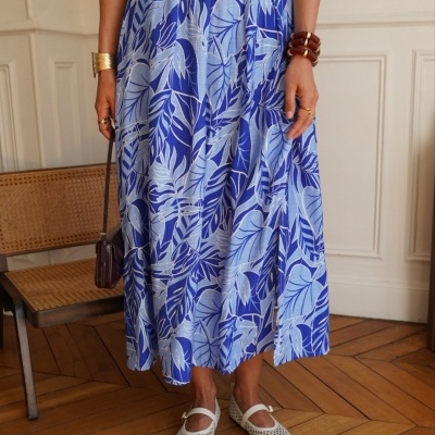 Saia midi azul com padrão de folhas em tons azuis e sapatos brancos em ambiente interior