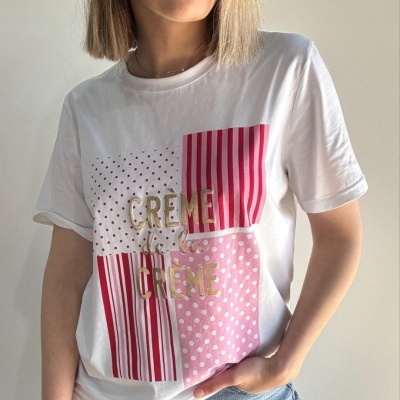 T-shirt branca com padrão rosa e texto dourado CRÈME de la CRÈME