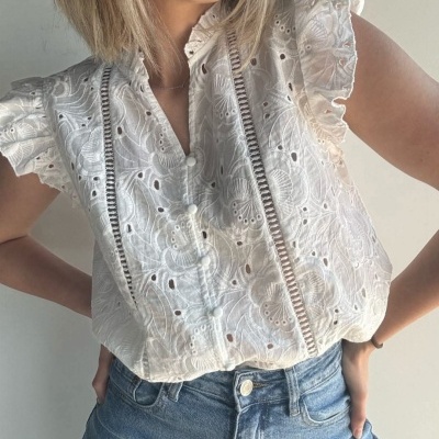Blusa branca bordada com mangas de babados e calças jeans azuis