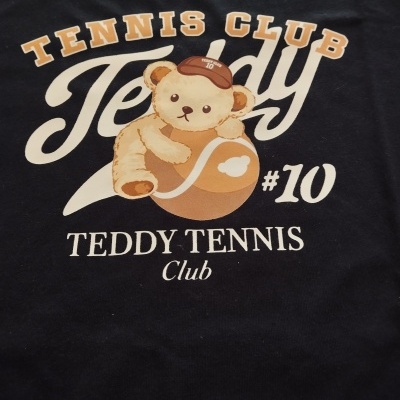 T-shirt preta com desenho de urso teddy e bola de ténis com texto