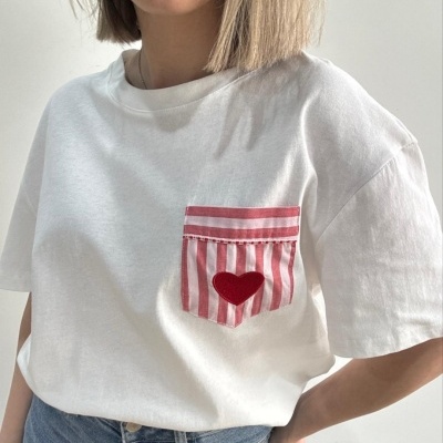 T-shirt branca com bolso riscado vermelho e branco e coração vermelho
