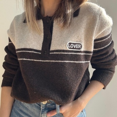 Camisola de malha castanha com riscas brancas e bordado LOVER, usada com calças de ganga.