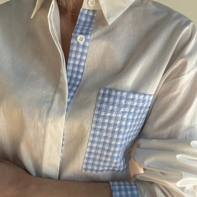 Camisa branca com detalhes xadrez azul e branco e botões brancos.