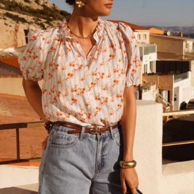 Blusa feminina estampada com calção de ganga azul claro num cenário exterior de dia.
