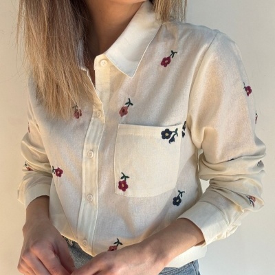 Camisa creme com bordados florais usada por mulher
