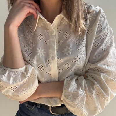 Blusa branca bordada com mangas compridas e jeans azul com cinto preto