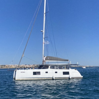 Catamarã branco com velas recolhidas no mar