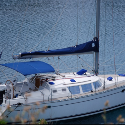 Veleiro branco e azul com vela e toldo azuis ancorado na água