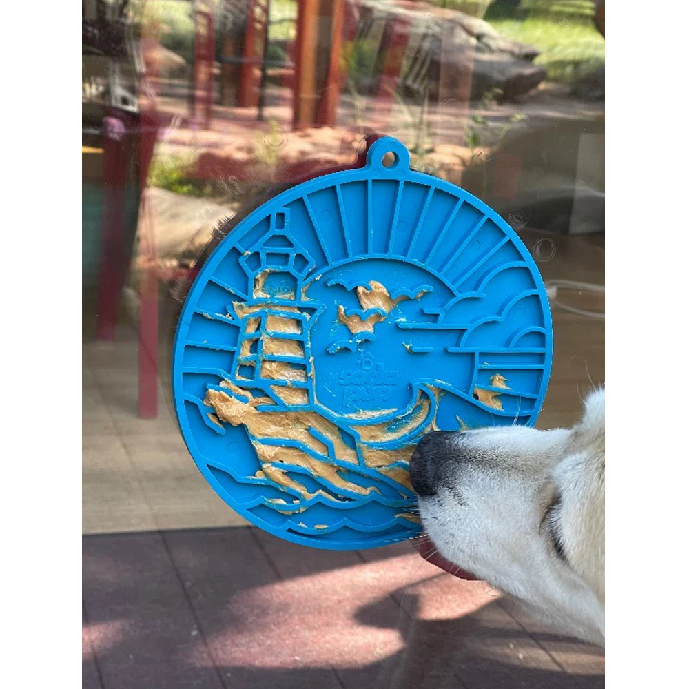 Tapete de lamber Lighthouse eMat! LickMat Ornamento decorativo azul redondo com recortado de farol e pássaros, junto ao focinho de um cão