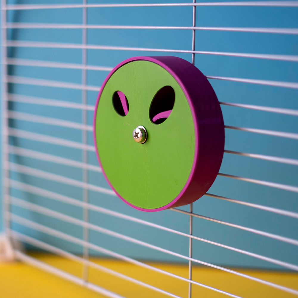 Large Foraging Wheel - tampa com 2 buracos Roda de exercício verde e roxa presa a uma grade metálica branca