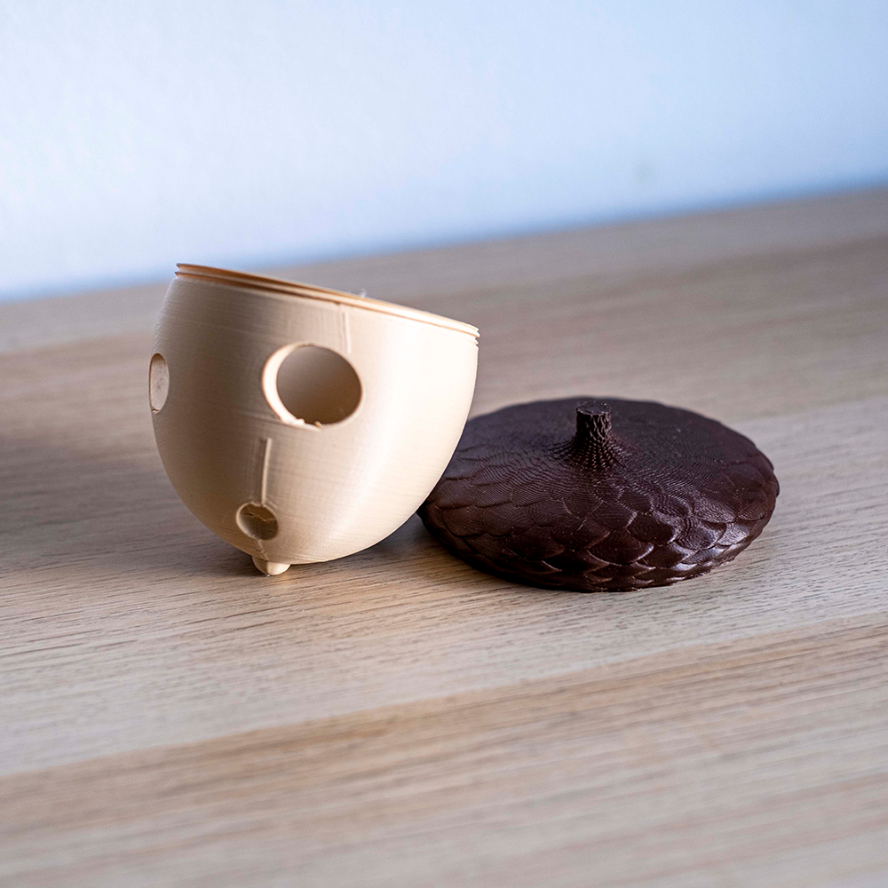 Rolling Acorn Vaso pequeno bege com buracos e tampa castanha texturizada sobre madeira