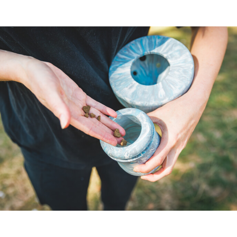 Porcini™ Dog Toy TOY - Blue Prism Pessoa a colocar ração num recipiente de cerâmica azul marmoreada ao ar livre