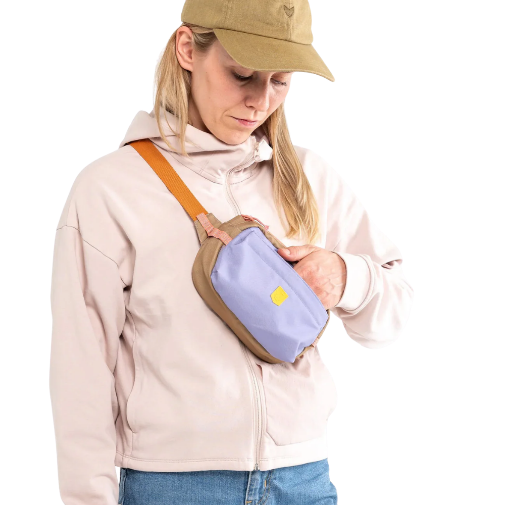 Alpha 360 - Bolsa - lavanda Mala pochete castanho e azul claro com alça laranja usada por mulher com casaco bege claro e boné castanho