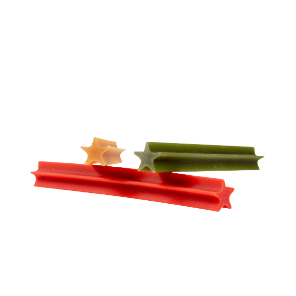 Garden Bites Dental Sticks - Snacks de Vegetais para Cães Três paus de massa estrelada em vermelho, verde e bege num fundo branco.