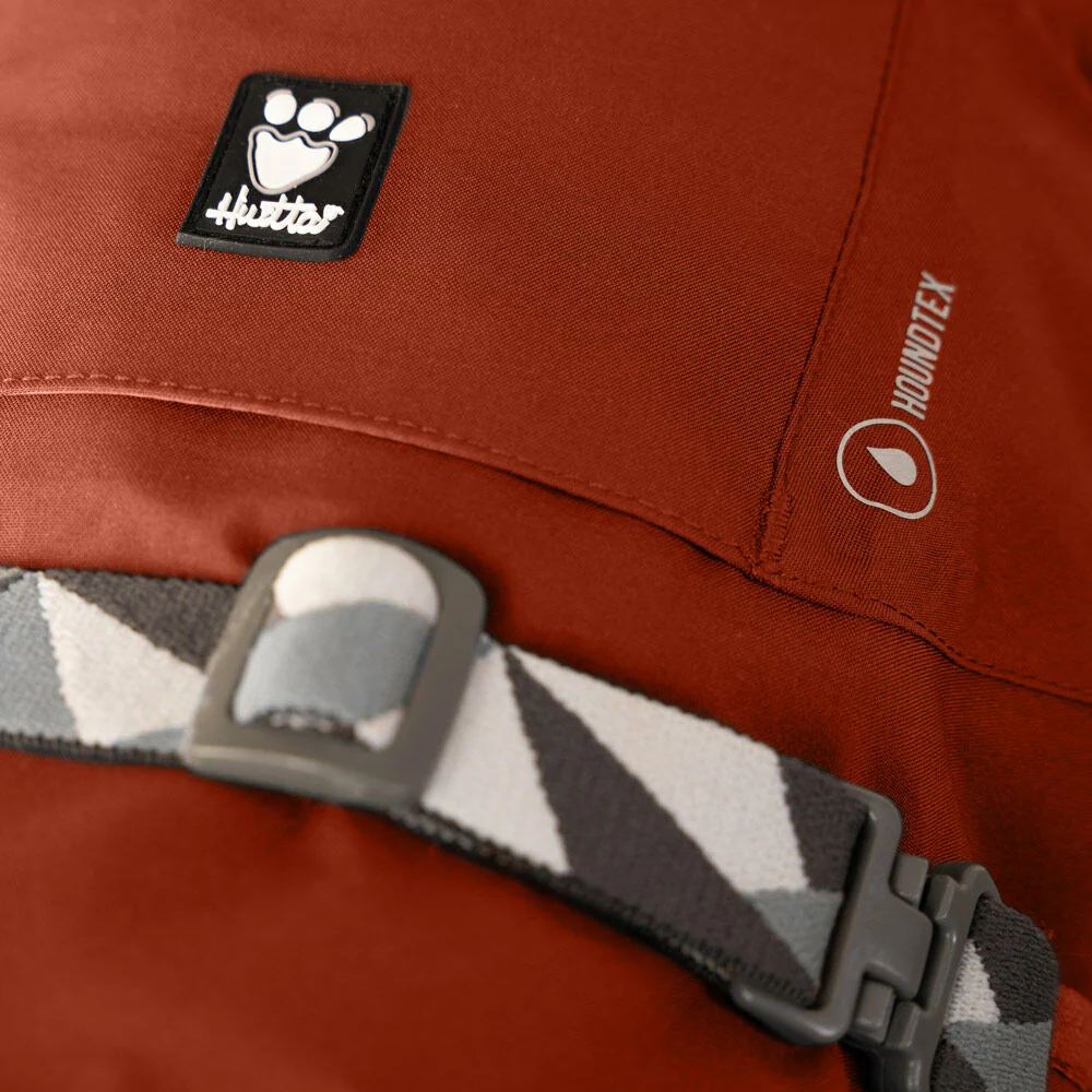 Mudventure Dog Coat ECO - Blackberry - Capa da Chuva - Hurtta Casaco vermelho com logotipo Hurtta e tira ajustável cinza, branca e preta com fivela.