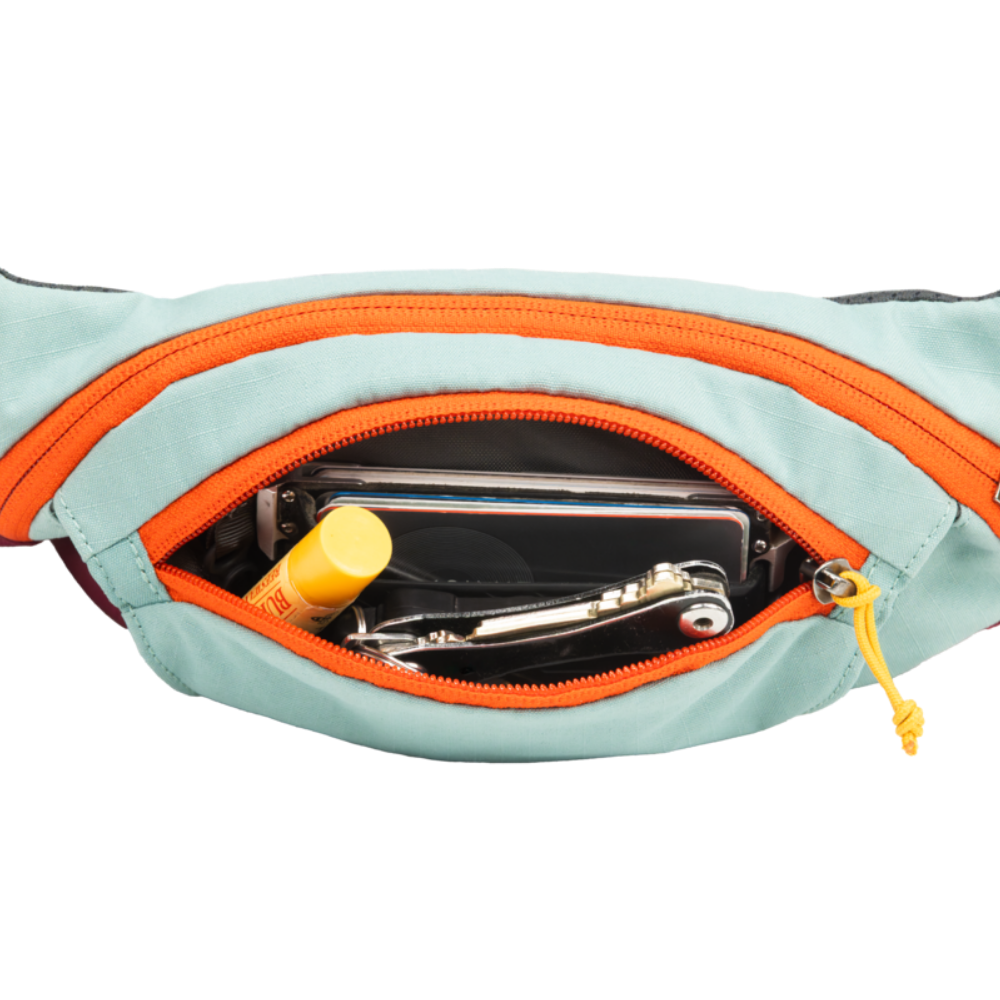 HOME TRAIL™ HIP PACK - River Rock Green - Ruffwear Bolsa cintura azul com zíper laranja aberta mostrando telemóvel, batom amarelo e chaves