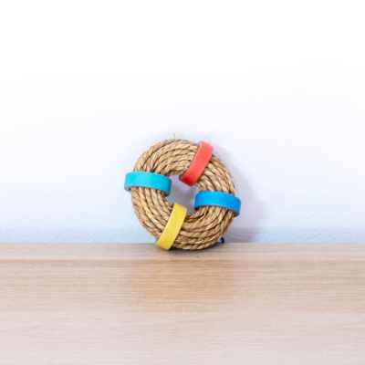 Brinquedo circular de corda com argolas coloridas sobre mesa de madeira
