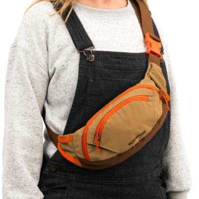 Bolsa transversal castanha e bege com fechos laranja e etiqueta RUFFWEAR usada com camisola cinza e macacão de ganga