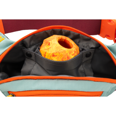 Mochila azul claro com detalhe laranja aberta mostrando bola laranja marmoreada dentro de bolso cinzento.