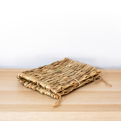 Esteira de fibras naturais dobrada sobre mesa de madeira clara