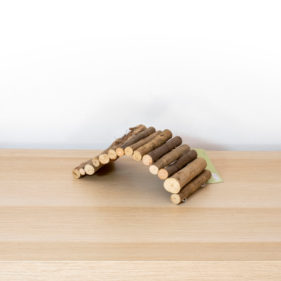 Estrutura curva de ramos de madeira com casca sobre mesa de madeira clara