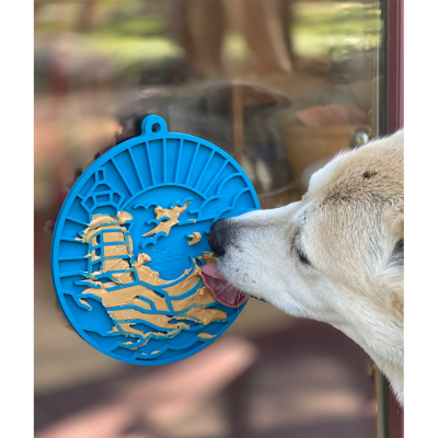 Decoração azul com relevo dourado de navio e gaivotas na superfície de vidro com cão branco a lamber.