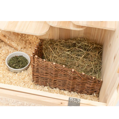 Cesto de vime com palha dentro e recipiente branco com ervas verdes em ambiente de madeira