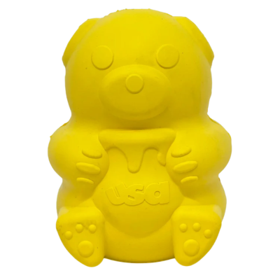 Brinquedo amarelo em formato de urso com pote e texto usa
