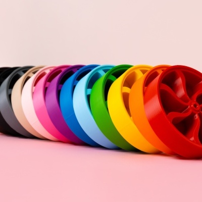 Tambores plásticos coloridos alinhados em superfície rosa