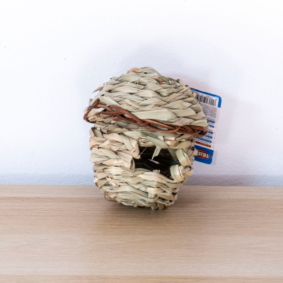 Casa de palha trançada para pequenos animais numa superfície de madeira