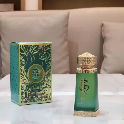 Frasco de perfume verde com tampa dourada ao lado da sua caixa decorativa na mesa